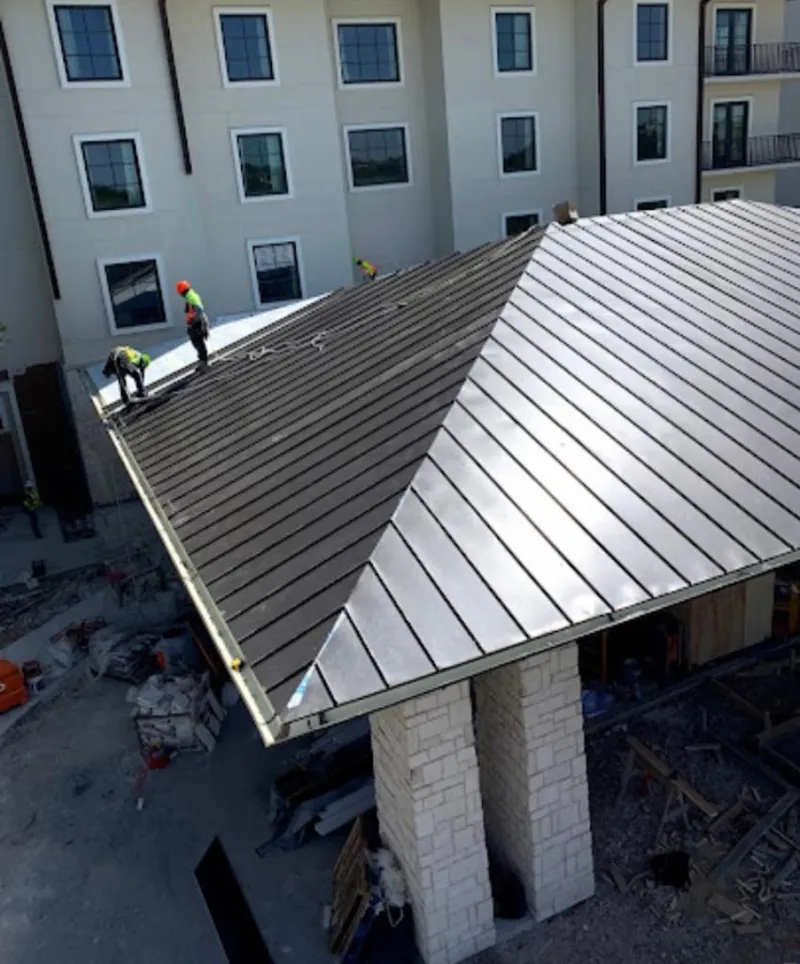 Crew installing standing seam metal roof panels on a commercial project in Geneseo